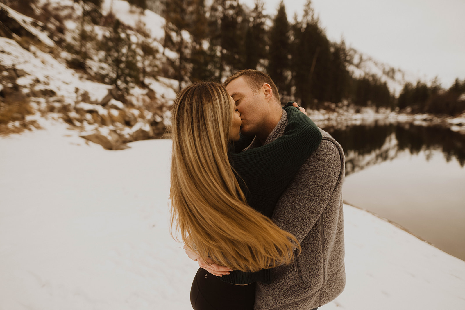 couple kisses on the snowy banks beach on the payette river
