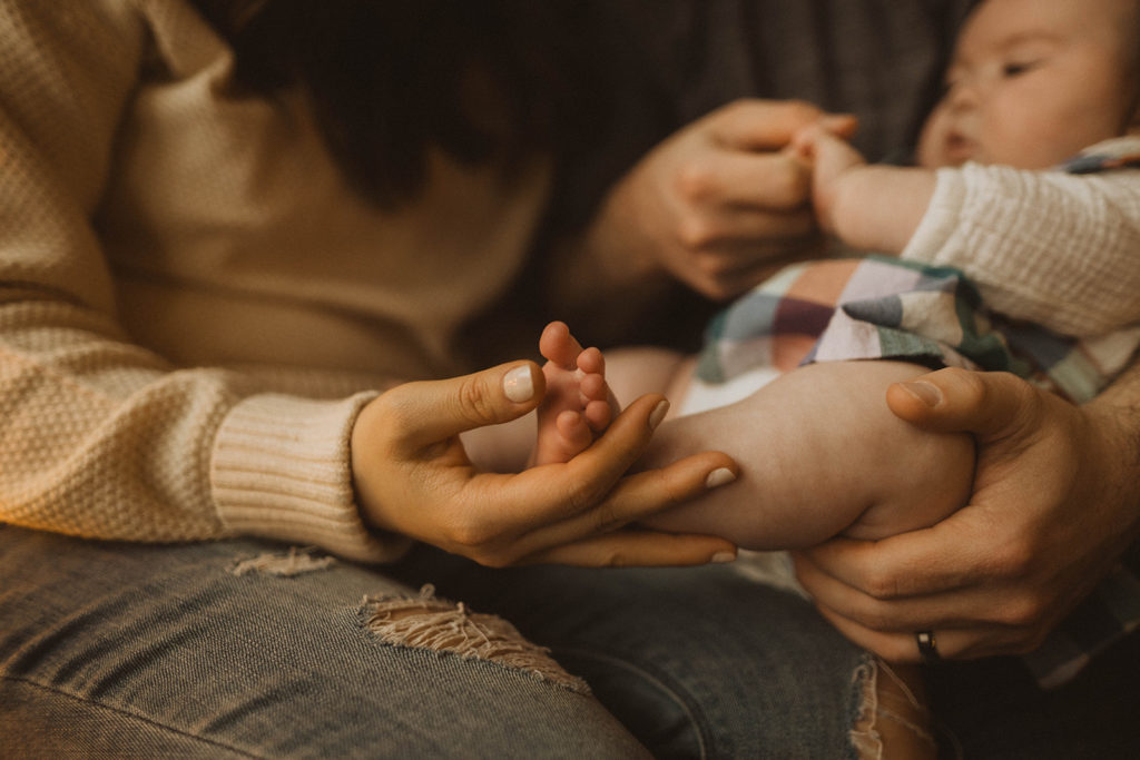 close up photo of mom playing with her newborn daughters little feet during their in-home family session