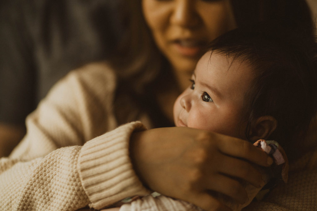 baby looks out the window as her mom holds her during their Seattle family lifestyle session