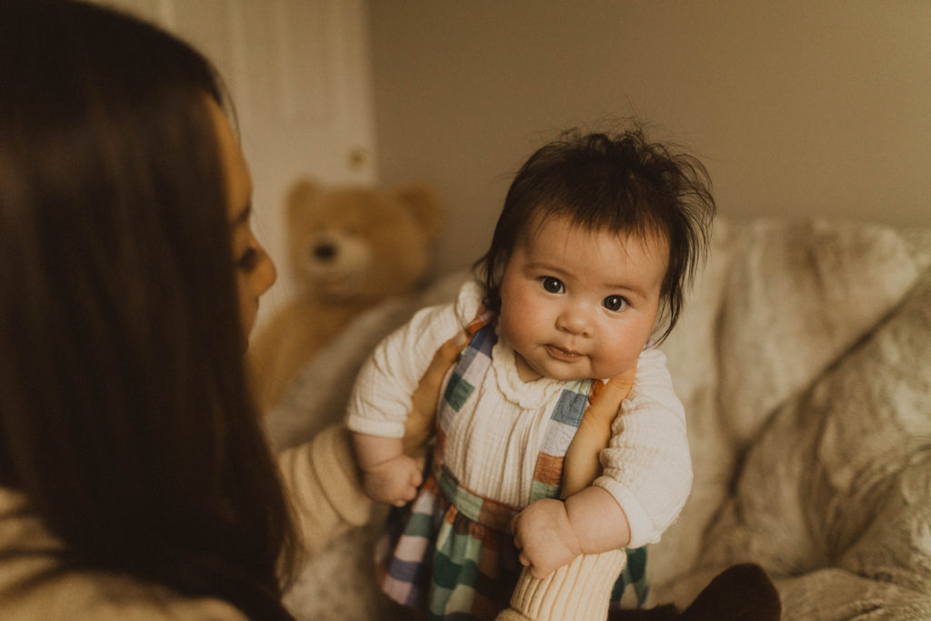 mom holds her baby as she stares at the camera during their Seattle family lifestyle session