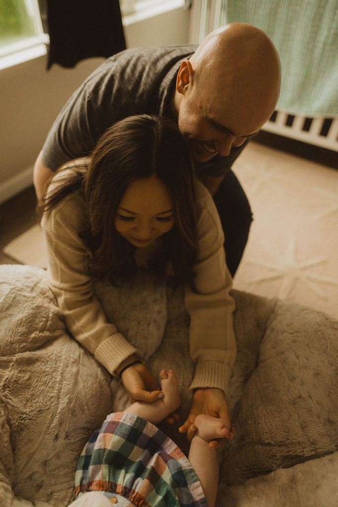 mom and dad play with baby's feet during their seattle family lifestyle session