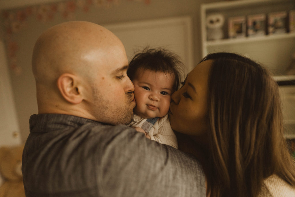new parents kiss their baby on the cheek during their seattle family lifestyle session