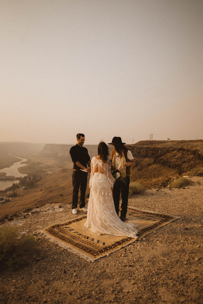 Two brides stand on the rim of the snake river canyon during their Idaho elopement ceremony