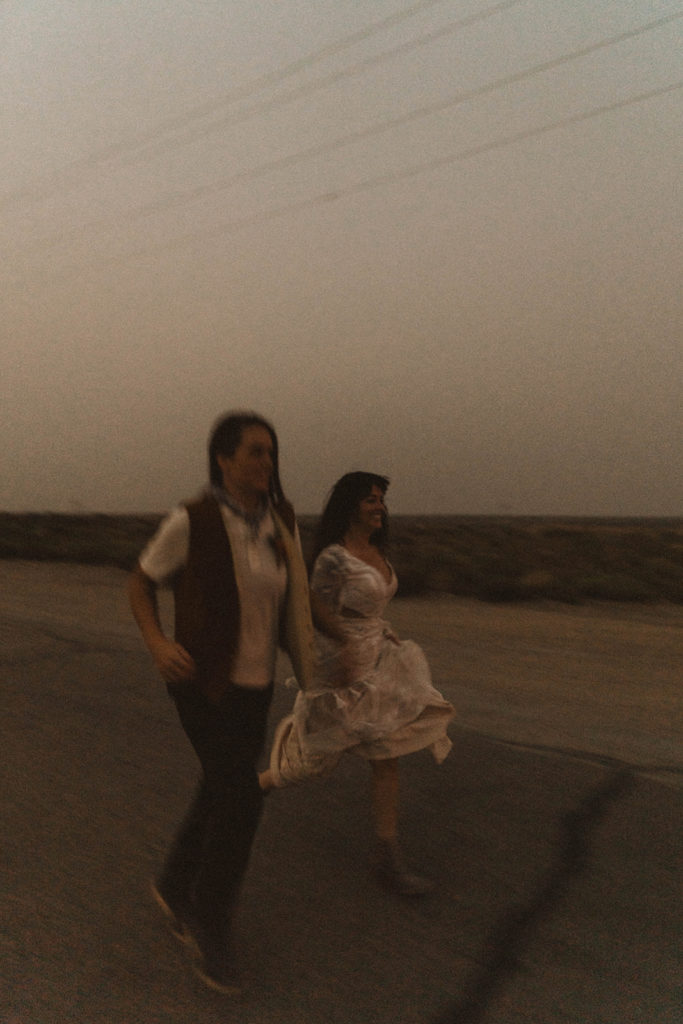 blurry elopement photo of brides running along the street at swan falls dam