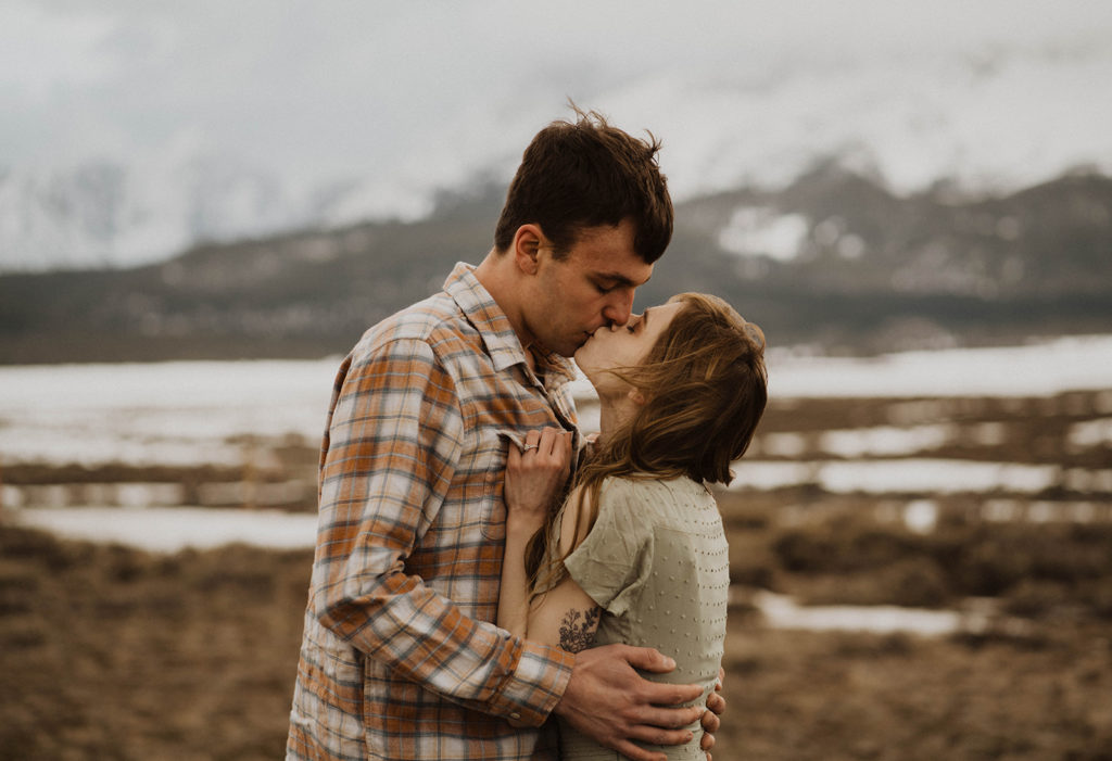 couple kisses with the sawtooth mountains in the background
